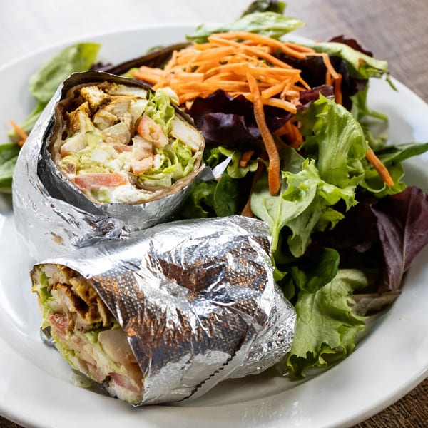 Two foil-wrapped breakfast burritos with chicken, lettuce, and tomato, served with a side salad.