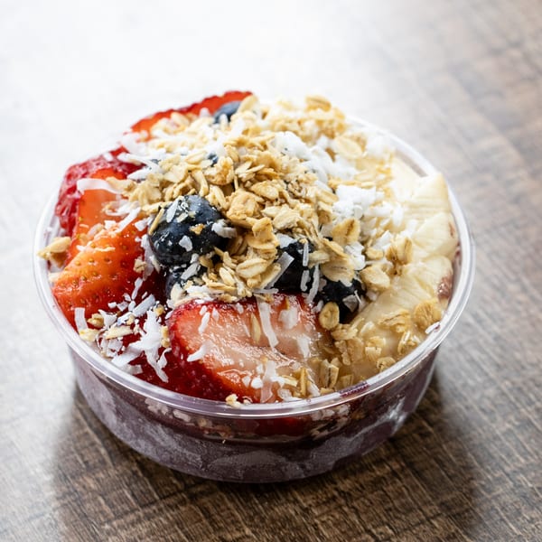 A Village Coffee acai bowl with strawberries, blueberries, bananas, granola, and coconut flakes.